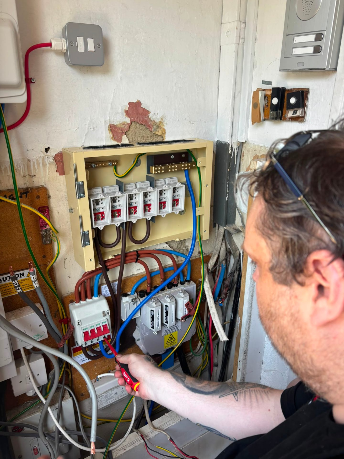 Electrician testing new fuse board with voltage tester