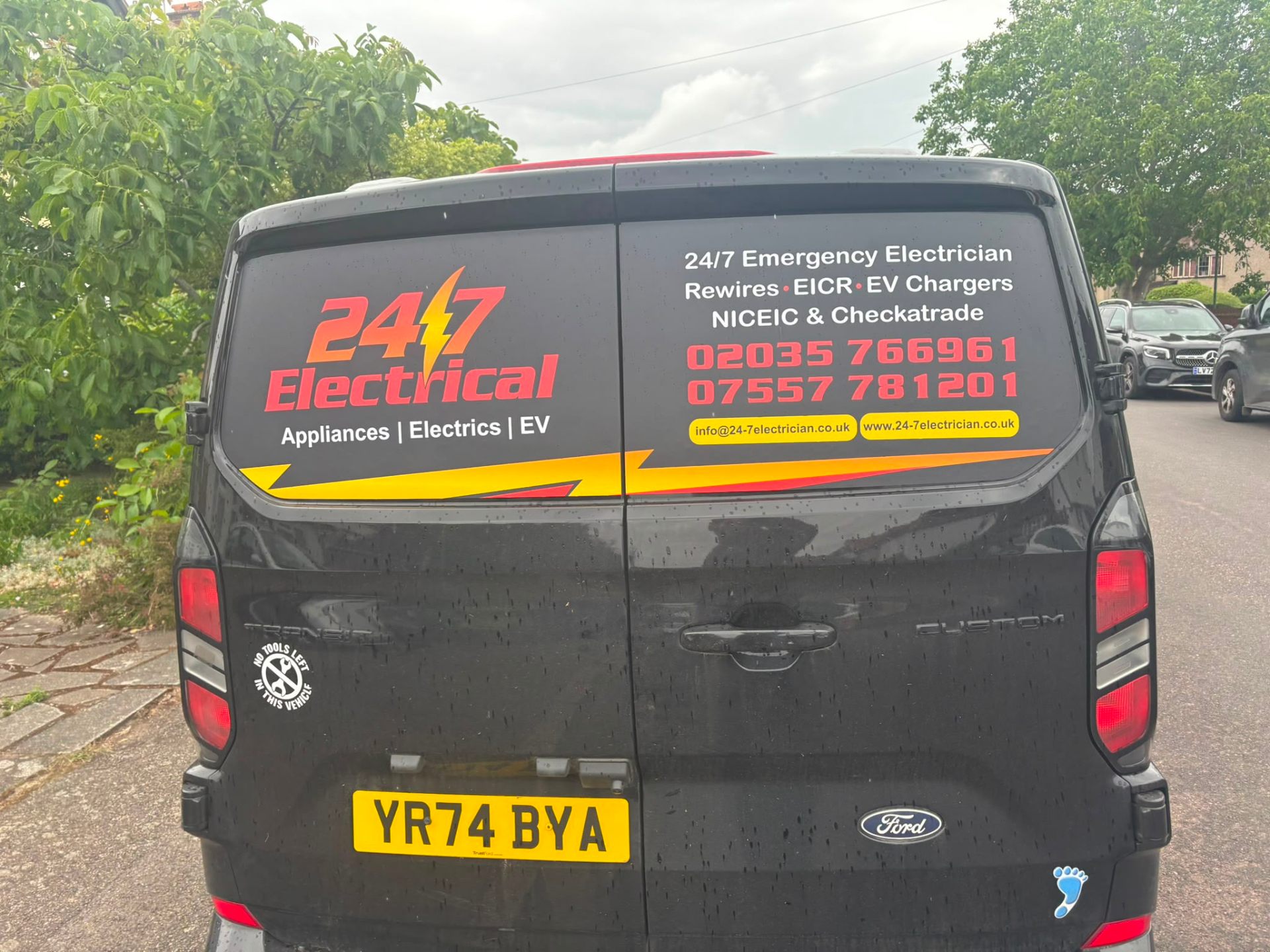 Rear of the 24/7 Electrical Ford Transit Custom van showing NICEIC and Checkatrade credentials