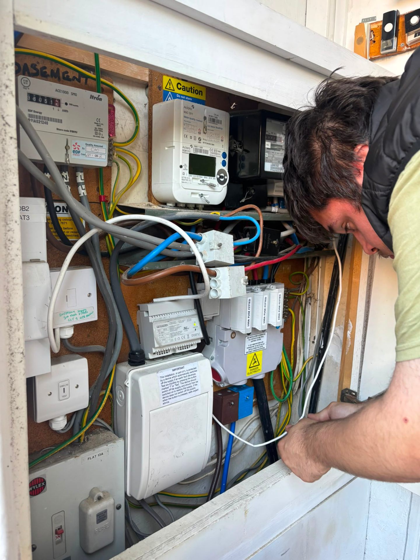 Electrician working on meter cupboard fuse arrangement