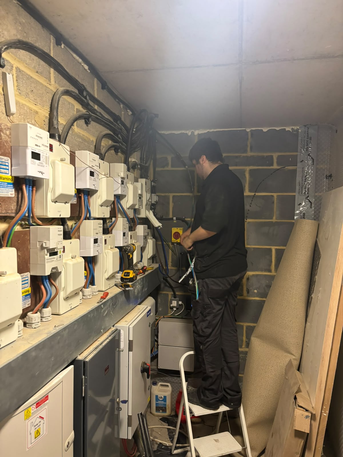 Engineer working on a block of meters during a communal rewire