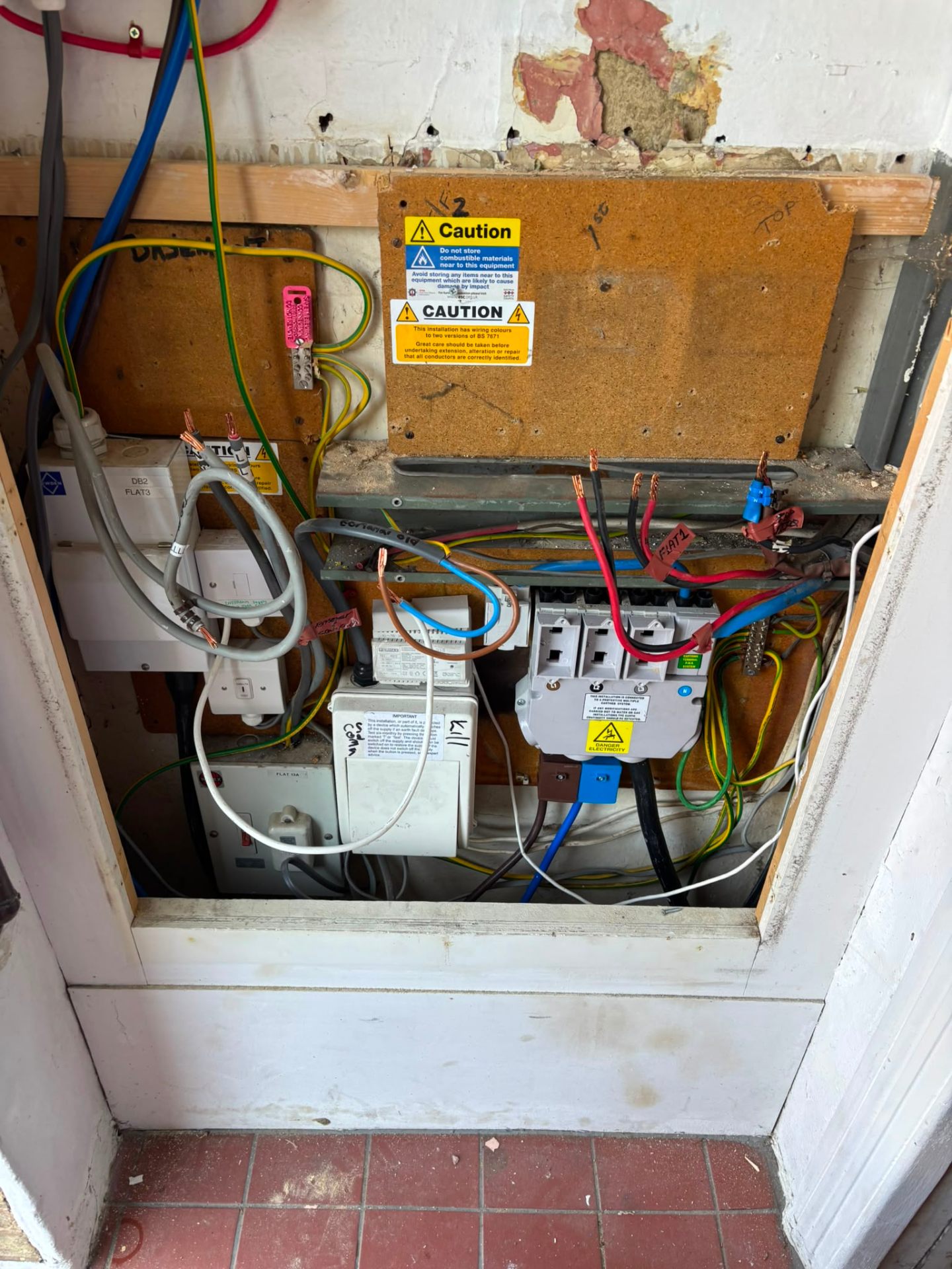 Old communal fuse board with mixed BS 7671 wiring before replacement