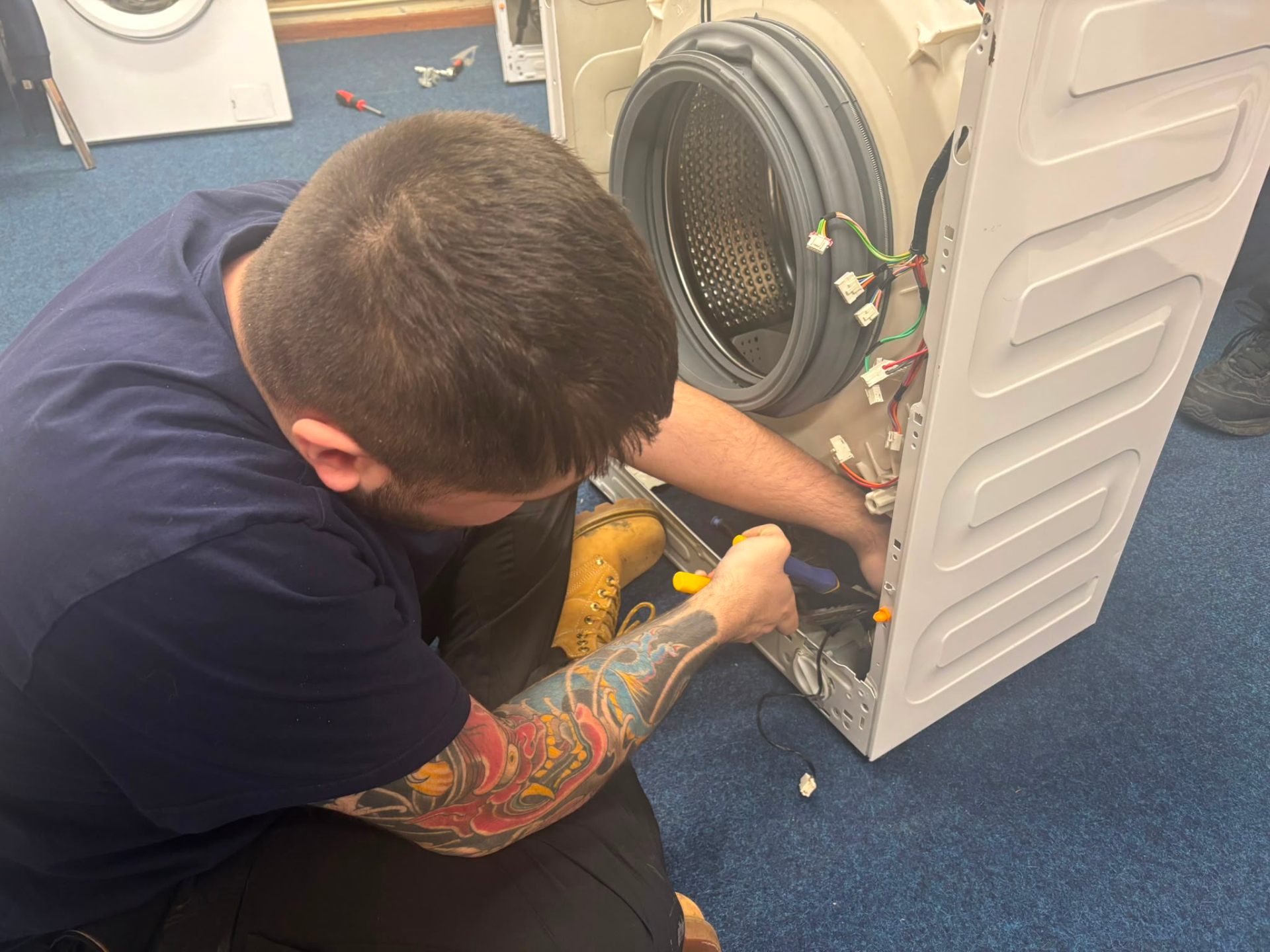 Engineer repairing the rear of a washing machine in our workshop