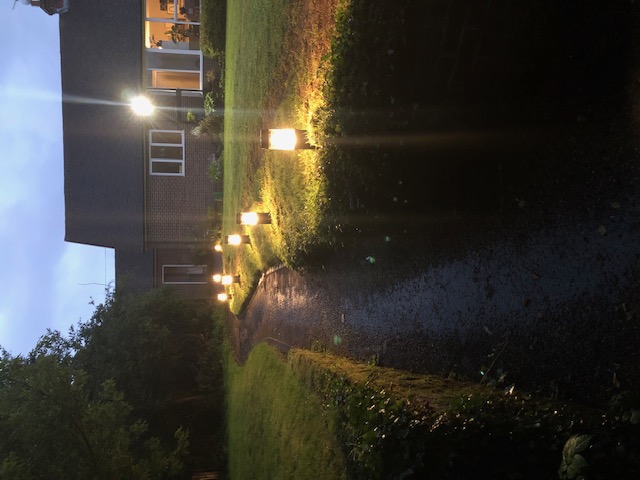Garden path lighting with house visible at twilight